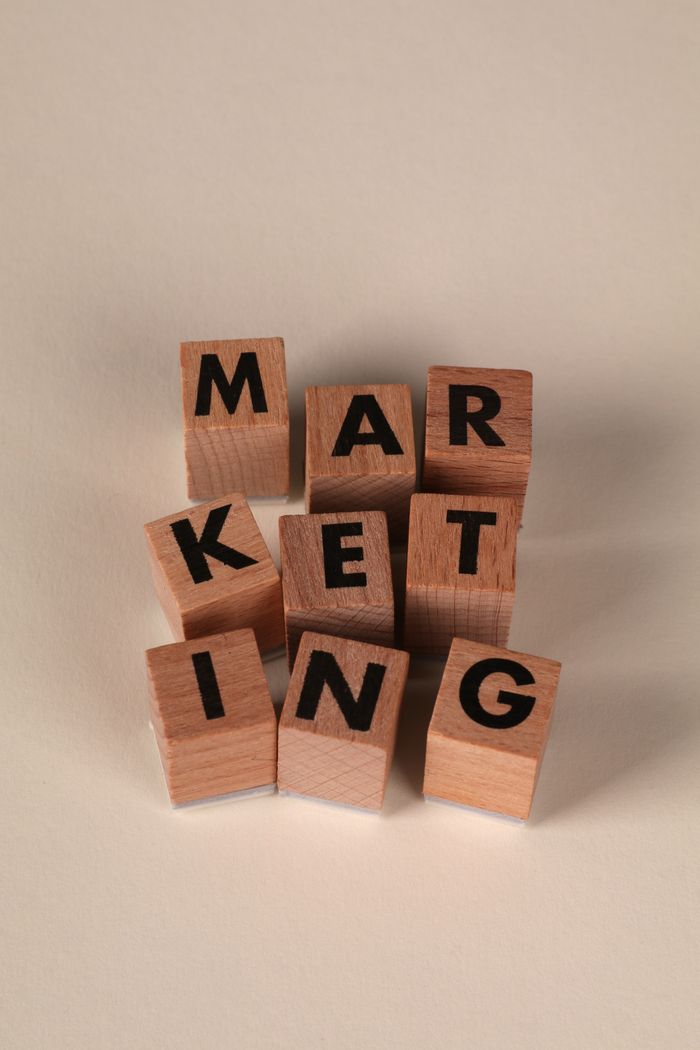 mission-img Wooden blocks arranged to spell MARKETING on a neutral background.